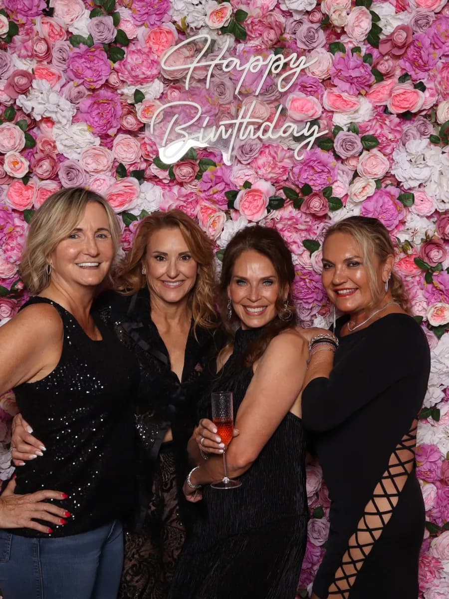 Birthday guests posing in front of a pink flower wall