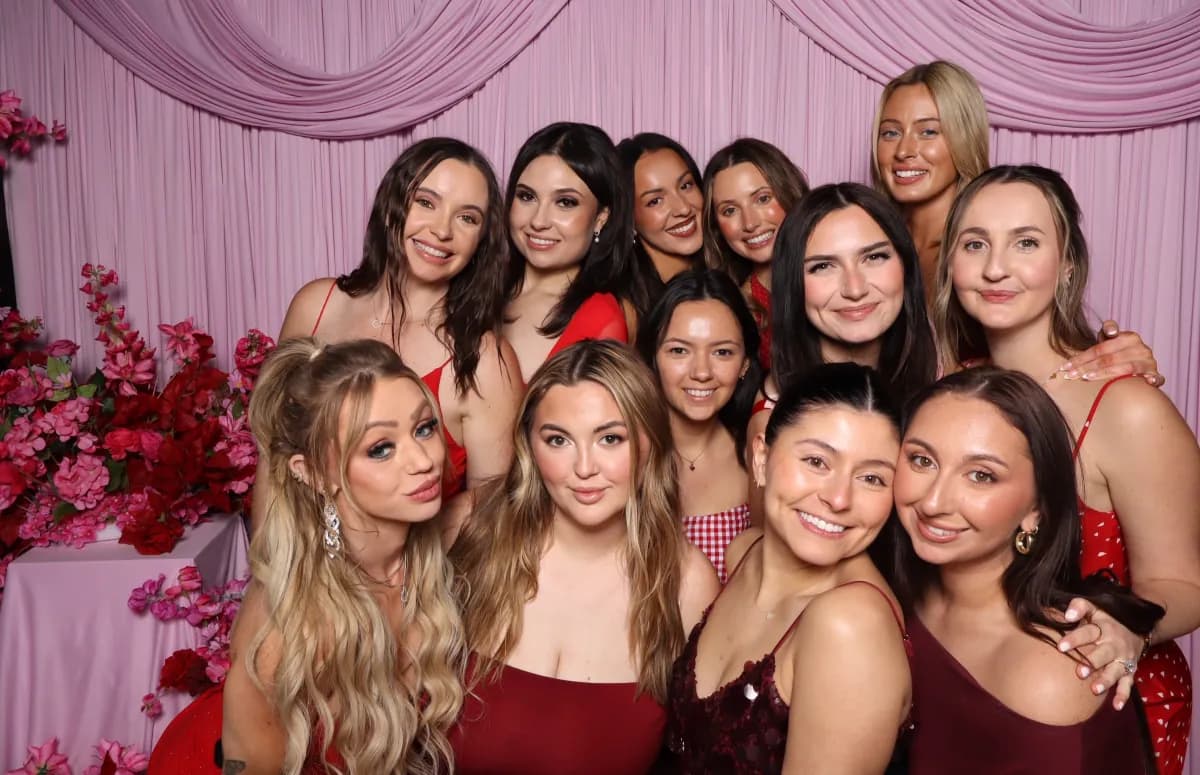 Event guests posing together against a pink backdrop
